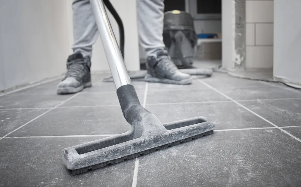 Industrial vacuum head clearing dust from a tiled construction floor