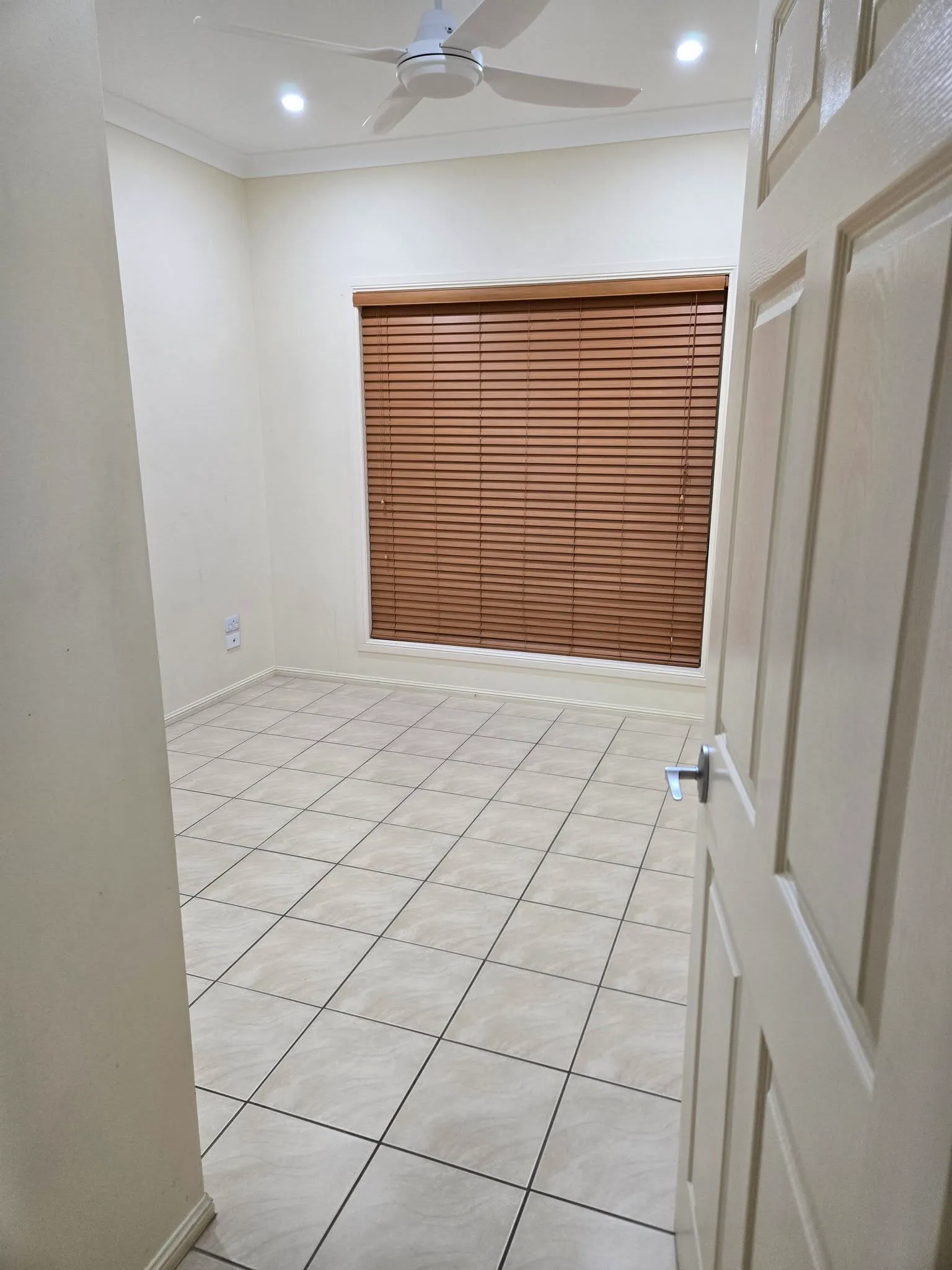 Empty tiled room with timber venetian blinds and ceiling fan