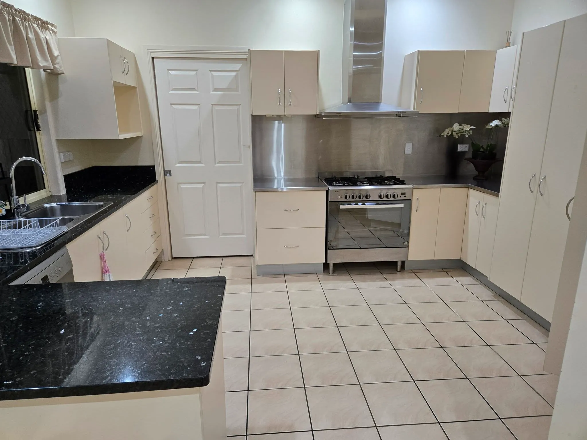 Tidy kitchen with stainless gas oven, range hood and stone benchtops